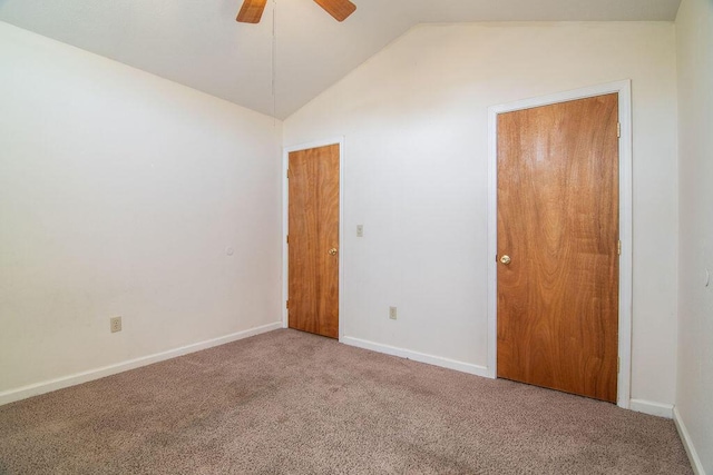 carpeted spare room featuring baseboards, vaulted ceiling, and a ceiling fan