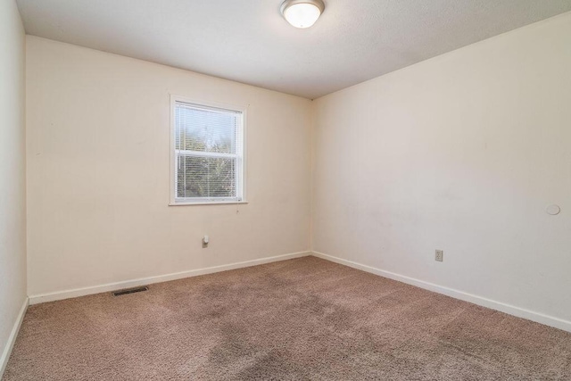 empty room with carpet flooring, visible vents, and baseboards