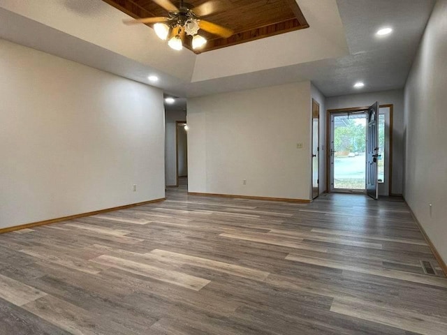 unfurnished room with dark wood-type flooring, a tray ceiling, baseboards, and recessed lighting