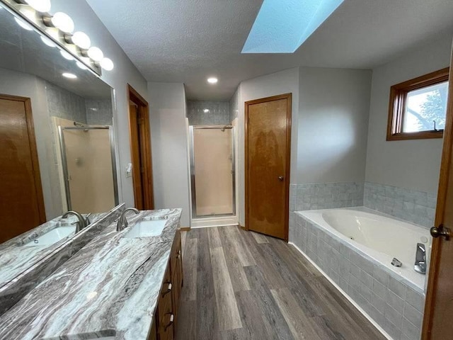 bathroom with a stall shower, a skylight, wood finished floors, and vanity