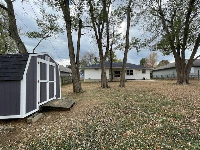 view of yard featuring a storage shed, fence, and an outbuilding