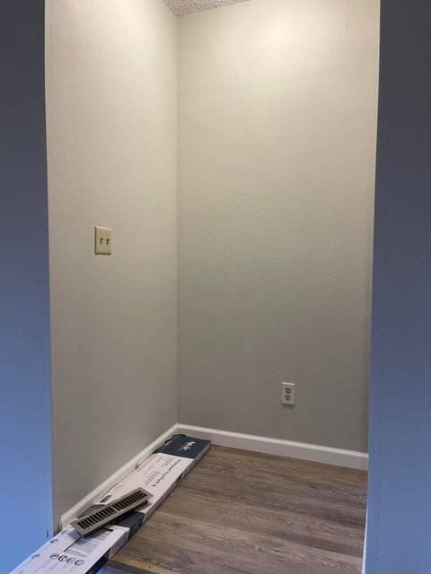 spare room with dark wood-style flooring, a textured ceiling, and baseboards