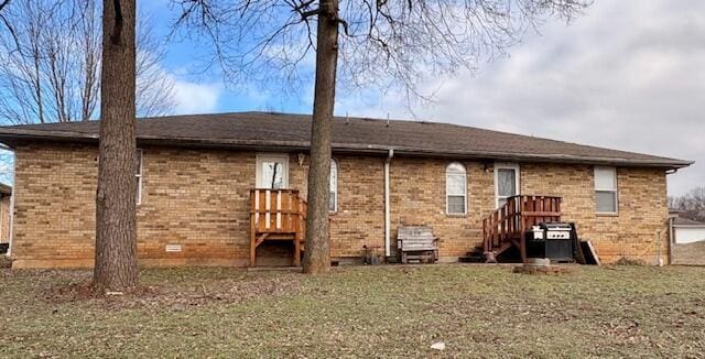 rear view of property with crawl space, a lawn, and brick siding