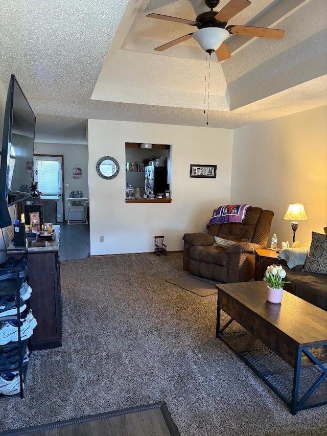 carpeted living room with a tray ceiling, a textured ceiling, and ceiling fan