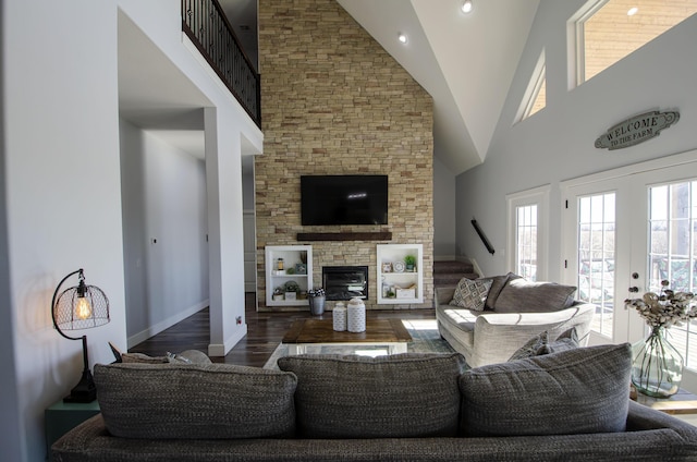 living area featuring dark wood finished floors, stairs, french doors, a fireplace, and high vaulted ceiling