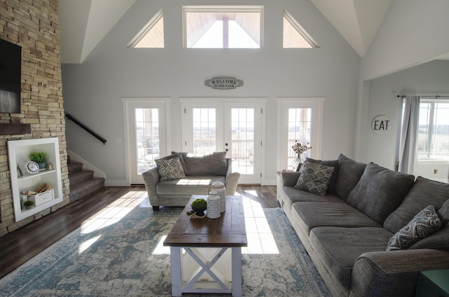 living area featuring dark wood-style floors, high vaulted ceiling, french doors, and stairway