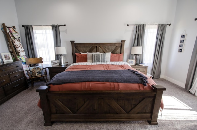 bedroom with baseboards, multiple windows, and light colored carpet