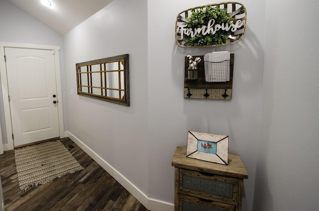 doorway with dark wood-style floors, baseboards, and vaulted ceiling