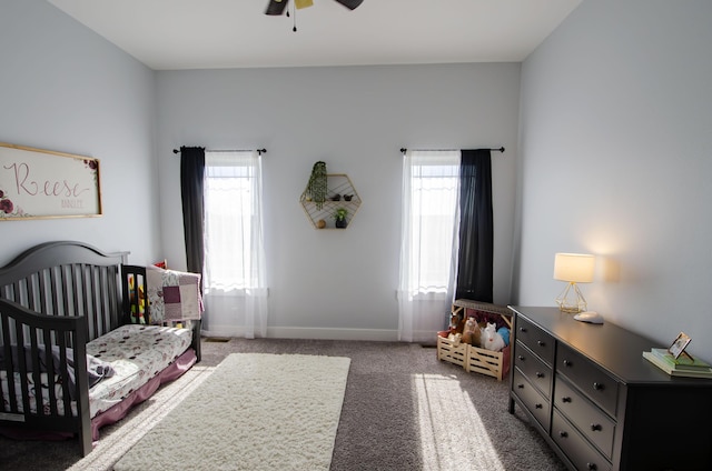 bedroom with a nursery area, multiple windows, dark carpet, and baseboards