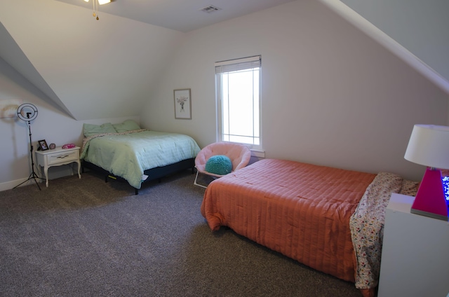 bedroom featuring lofted ceiling, dark colored carpet, and visible vents