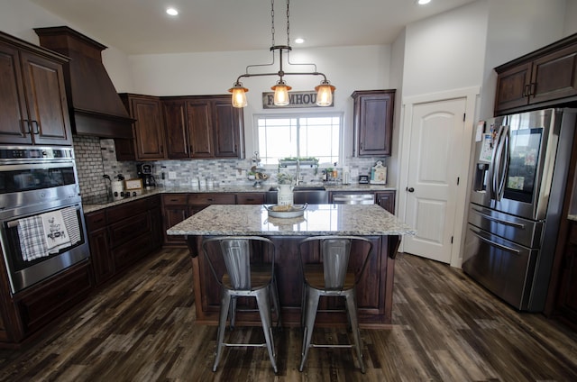 kitchen featuring dark brown cabinetry, a kitchen island, stainless steel appliances, and decorative light fixtures