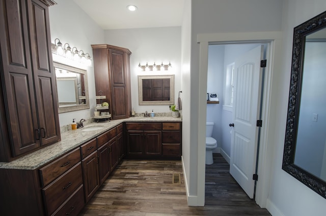 bathroom featuring recessed lighting, toilet, vanity, wood finished floors, and baseboards