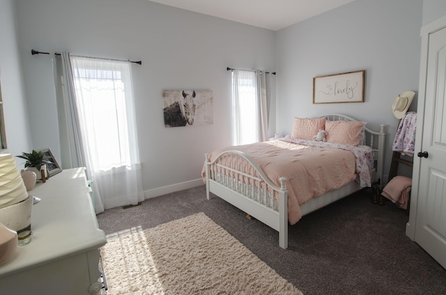 bedroom with dark carpet and baseboards