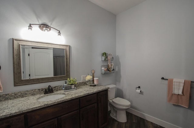 full bath with toilet, wood finished floors, vanity, and baseboards