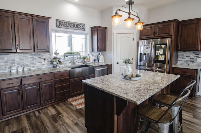 kitchen with pendant lighting, appliances with stainless steel finishes, dark brown cabinetry, and a center island