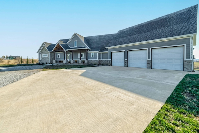 craftsman house featuring an attached garage, concrete driveway, roof with shingles, and stone siding