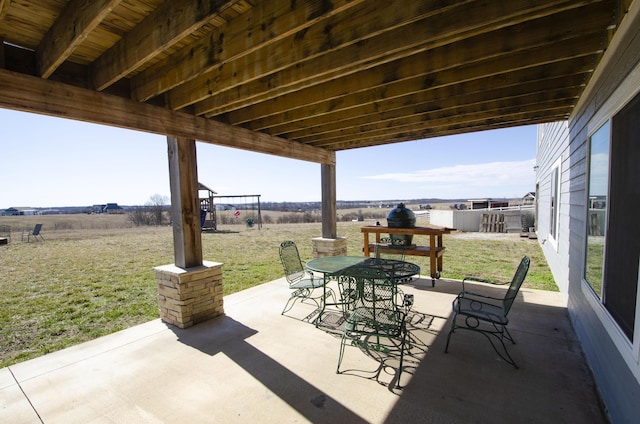 view of patio / terrace with a rural view, outdoor dining area, and a playground