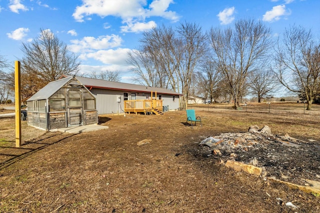 exterior space with a greenhouse, a deck, and an outdoor structure