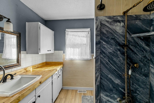 kitchen featuring visible vents, white cabinetry, light countertops, and a sink