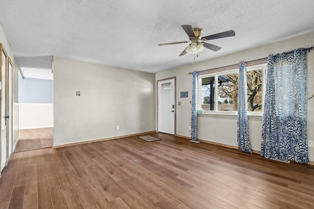 foyer with ceiling fan, a textured ceiling, baseboards, and wood finished floors