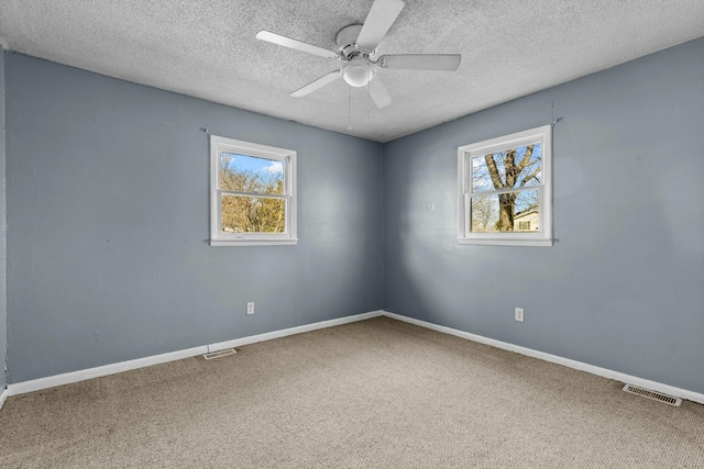 carpeted empty room featuring a healthy amount of sunlight, visible vents, and baseboards