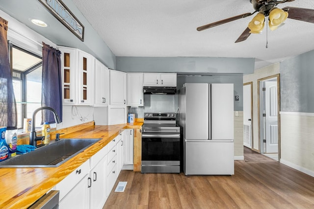 kitchen with stainless steel electric range oven, glass insert cabinets, freestanding refrigerator, a sink, and under cabinet range hood