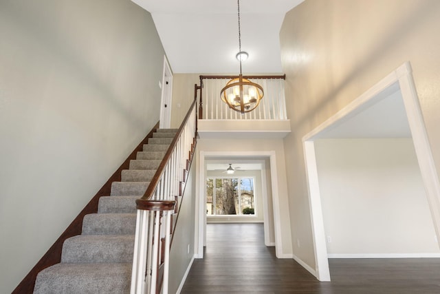 entryway with a high ceiling, baseboards, stairs, dark wood finished floors, and an inviting chandelier