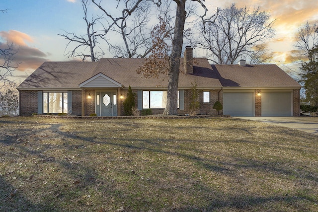 view of front of house featuring a garage, concrete driveway, a chimney, a front lawn, and brick siding