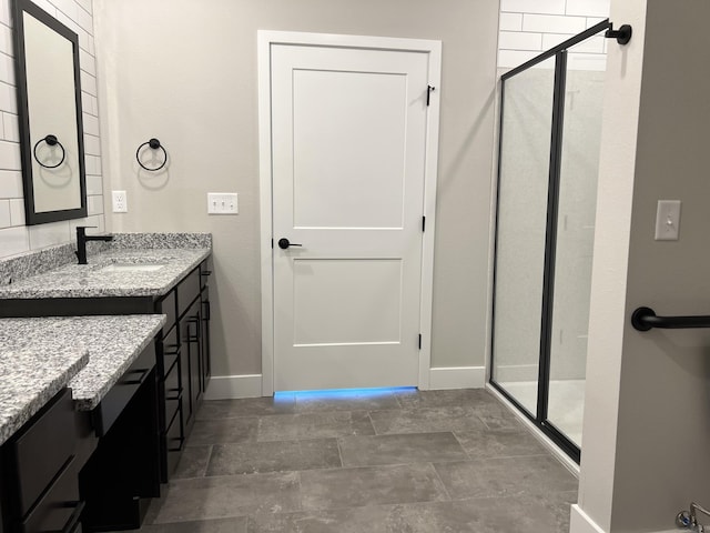 full bath featuring a stall shower, vanity, and baseboards