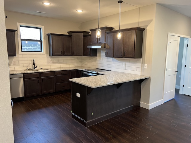 kitchen with appliances with stainless steel finishes, a kitchen breakfast bar, a peninsula, hanging light fixtures, and a sink