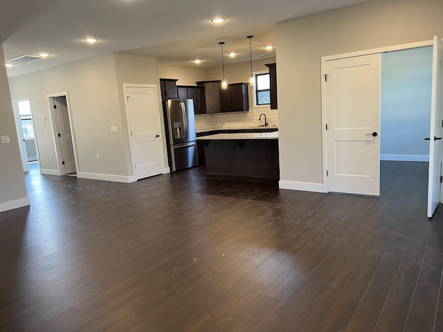 kitchen with stainless steel fridge, dark wood finished floors, light countertops, pendant lighting, and a sink