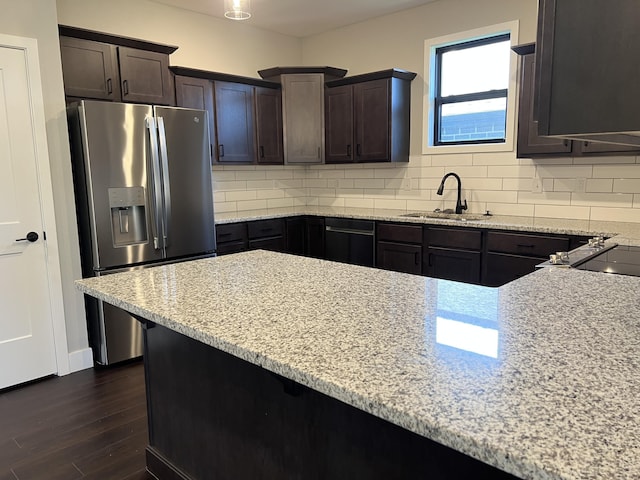 kitchen with tasteful backsplash, light stone counters, stainless steel refrigerator with ice dispenser, and a sink