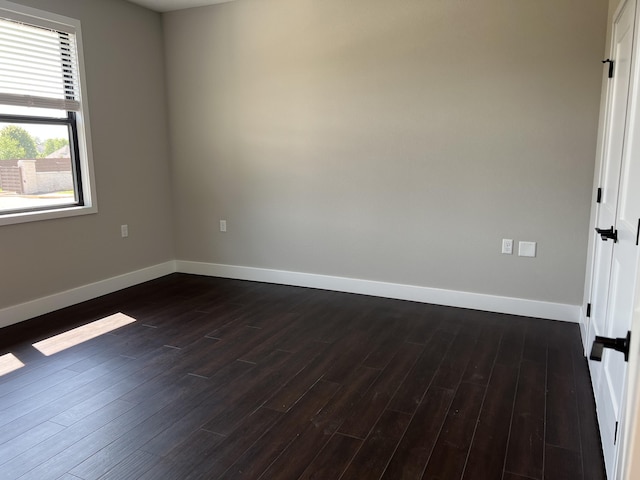 empty room featuring dark wood-style flooring and baseboards