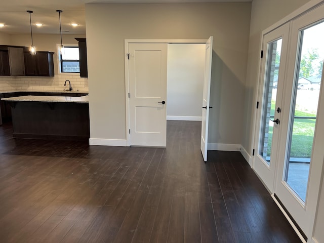 kitchen with a breakfast bar area, dark wood-style flooring, baseboards, tasteful backsplash, and decorative light fixtures