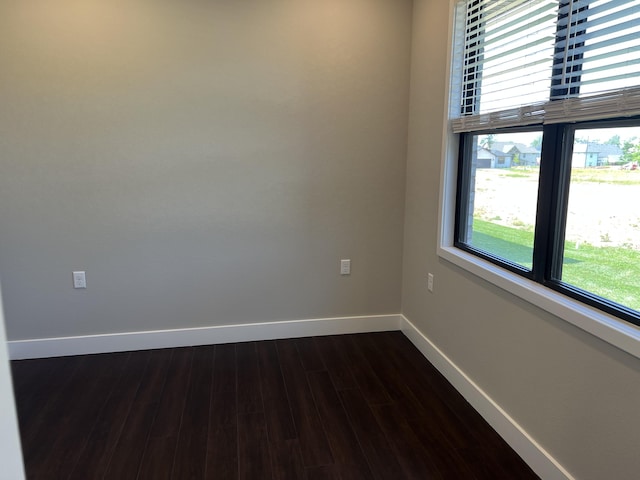 spare room featuring dark wood-style floors and baseboards