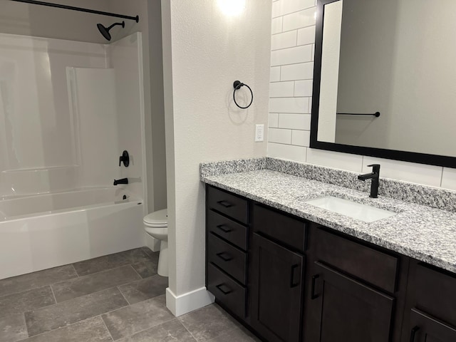 full bathroom featuring toilet, stone finish flooring, vanity,  shower combination, and baseboards