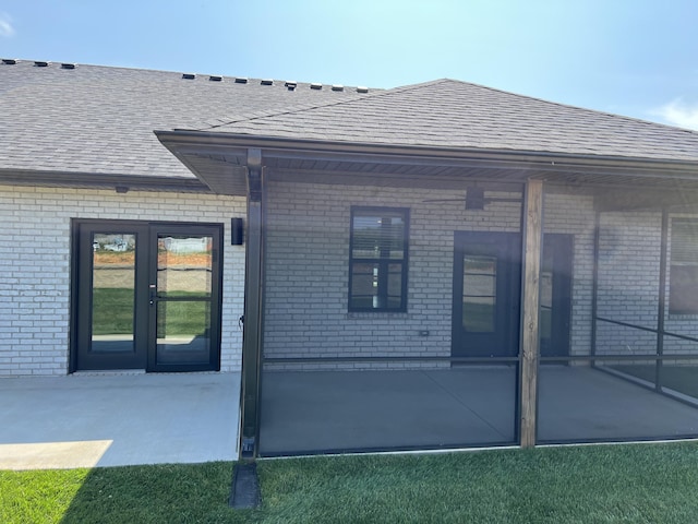 rear view of house with a patio, brick siding, and roof with shingles