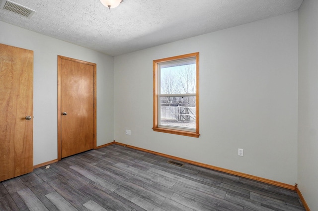 unfurnished bedroom featuring a textured ceiling, wood finished floors, visible vents, and baseboards