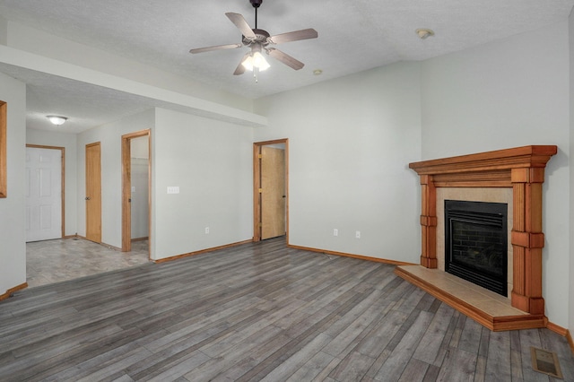 unfurnished living room with baseboards, visible vents, wood finished floors, a textured ceiling, and a fireplace