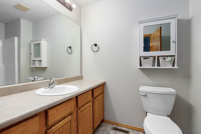 bathroom featuring toilet, visible vents, a textured ceiling, and vanity