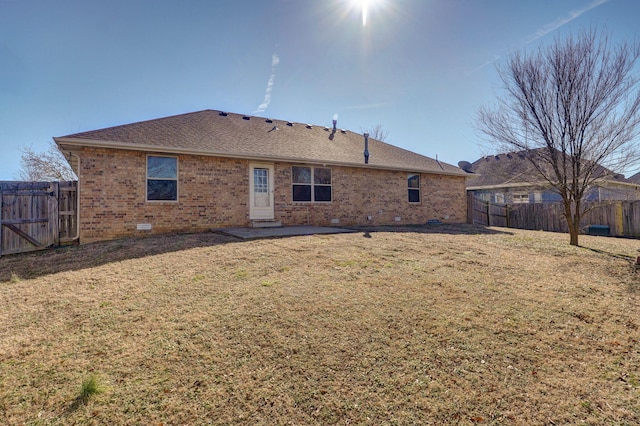 back of house featuring brick siding, a shingled roof, a lawn, crawl space, and a fenced backyard