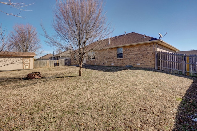 view of yard with a storage shed, a fenced backyard, and an outdoor structure