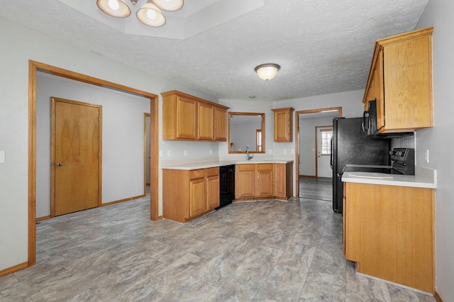 kitchen with light countertops, black appliances, a sink, and baseboards