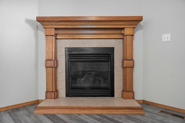 room details with baseboards, visible vents, wood finished floors, and a tile fireplace