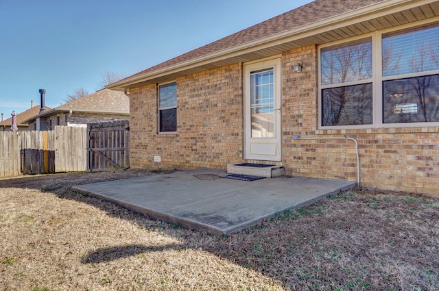 back of property with brick siding, a patio, and fence