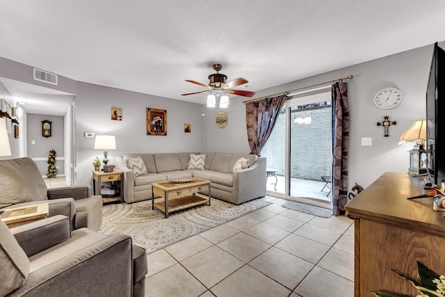 living room with a ceiling fan, visible vents, a textured ceiling, and light tile patterned floors