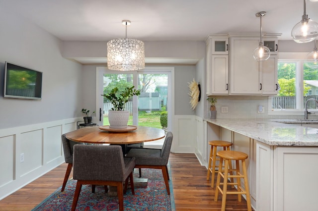 dining area featuring a wainscoted wall, dark wood finished floors, and a decorative wall