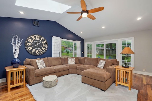 living area featuring ceiling fan, vaulted ceiling with skylight, recessed lighting, baseboards, and light wood-type flooring