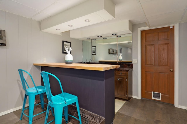 bar featuring indoor wet bar, visible vents, baseboards, and wood finished floors