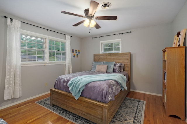 bedroom featuring light wood-style floors, baseboards, visible vents, and a ceiling fan